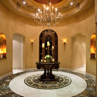 На фото: класса люкс огромные фойе в классическом стиле с бежевыми стенами, полом из известняка, одностворчатой входной дверью и входной дверью из темного дерева