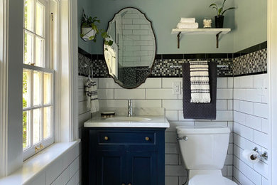 Mid-sized trendy white tile and porcelain tile ceramic tile, yellow floor and single-sink alcove shower photo in Other with shaker cabinets, a two-piece toilet, blue walls, an undermount sink, quartzite countertops, a hinged shower door, white countertops, a niche and a freestanding vanity