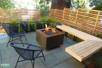 This is an example of a small contemporary front yard shaded driveway in Seattle with a fire feature and concrete pavers.