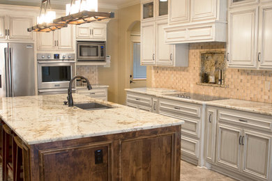 Large elegant beige floor open concept kitchen photo in Little Rock with an undermount sink, distressed cabinets, granite countertops, beige backsplash, stainless steel appliances, an island and raised-panel cabinets