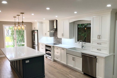 Inspiration for a mid-sized modern l-shaped light wood floor and beige floor kitchen pantry remodel in Other with a drop-in sink, shaker cabinets, white cabinets, quartz countertops, white backsplash, ceramic backsplash, stainless steel appliances and gray countertops