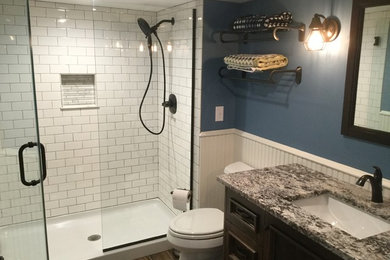 Alcove shower - mid-sized contemporary 3/4 white tile and subway tile vinyl floor and brown floor alcove shower idea in Minneapolis with recessed-panel cabinets, dark wood cabinets, a two-piece toilet, blue walls, an undermount sink, granite countertops, a hinged shower door and beige countertops