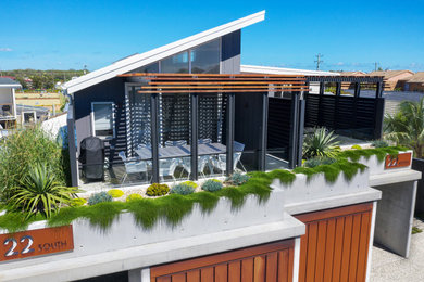 Imagen de fachada de casa bifamiliar blanca y blanca marinera de dos plantas con revestimiento de hormigón, tejado de metal y panel y listón