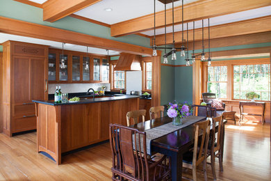 Open concept kitchen - mid-sized craftsman l-shaped light wood floor open concept kitchen idea in Boston with an undermount sink, shaker cabinets, medium tone wood cabinets, granite countertops, white backsplash, ceramic backsplash, paneled appliances and an island