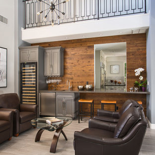 ロサンゼルスの中サイズのトランジショナルスタイルのおしゃれなウェットバー (アンダーカウンターシンク、落し込みパネル扉のキャビネット、グレーのキャビネット、クオーツストーンカウンター、茶色いキッチンパネル、木材のキッチンパネル、磁器タイルの床、グレーの床) の写真