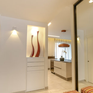 На фото: узкие прихожие в стиле модернизм с белыми стенами и гранитным полом