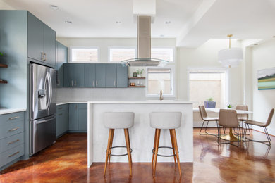 Mid-sized transitional l-shaped concrete floor and brown floor open concept kitchen photo in Austin with an undermount sink, flat-panel cabinets, green cabinets, quartz countertops, white backsplash, mosaic tile backsplash, stainless steel appliances, an island and white countertops