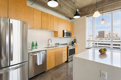Small urban single-wall concrete floor and gray floor open concept kitchen photo in Austin with an undermount sink, flat-panel cabinets, light wood cabinets, quartzite countertops, gray backsplash, ceramic backsplash, stainless steel appliances and an island