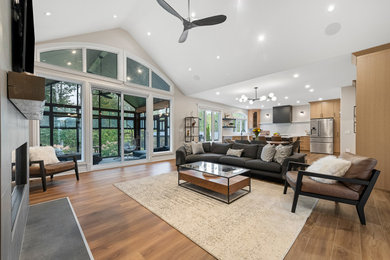 Inspiration for a large contemporary open concept vinyl floor, brown floor and vaulted ceiling living room remodel in Ottawa with white walls, a standard fireplace, a tile fireplace and a wall-mounted tv