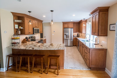 Inspiration for a mid-sized cottage l-shaped porcelain tile and beige floor eat-in kitchen remodel in Other with an undermount sink, shaker cabinets, brown cabinets, granite countertops, beige backsplash, subway tile backsplash, stainless steel appliances and beige countertops