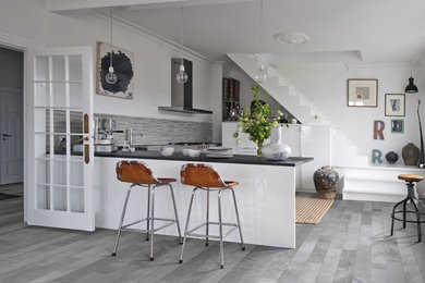 Small eclectic kitchen in Denver with flat-panel cabinets, white cabinets, porcelain splashback, stainless steel appliances, porcelain floors, a peninsula and grey floor.