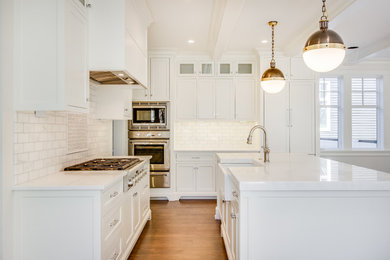 Open concept kitchen - modern medium tone wood floor and brown floor open concept kitchen idea in Detroit with a farmhouse sink, shaker cabinets, white cabinets, marble countertops, white backsplash, marble backsplash, stainless steel appliances, an island and white countertops