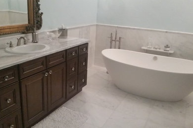 Bathroom - large transitional master white tile and marble tile marble floor and white floor bathroom idea in Tampa with recessed-panel cabinets, brown cabinets, a two-piece toilet, blue walls, a drop-in sink, marble countertops, a hinged shower door and white countertops