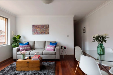 Photo of a small scandinavian open concept living room in Sydney with white walls, laminate floors, a freestanding tv and brown floor.