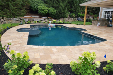 Foto de piscina natural tradicional de tamaño medio a medida en patio trasero con paisajismo de piscina y adoquines de hormigón