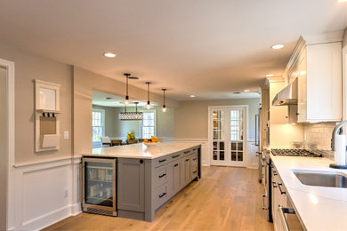 Example of a large transitional medium tone wood floor eat-in kitchen design in Boston with shaker cabinets, quartz countertops, gray backsplash, porcelain backsplash, stainless steel appliances, an island and multicolored countertops