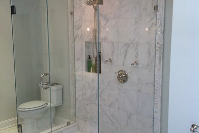 Large transitional master bathroom in New York with a two-piece toilet, gray tile, white tile, stone tile, grey walls and marble floors.