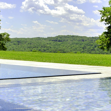 glass tile swimming pool + spa with perimeter overflow + granite decking