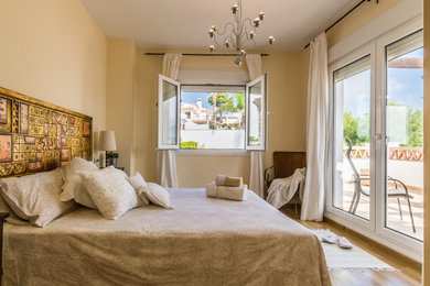 Diseño de dormitorio principal de estilo de casa de campo de tamaño medio con paredes beige, suelo de madera en tonos medios y suelo beige