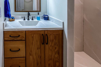 Small transitional 3/4 vinyl floor, gray floor and single-sink bathroom photo in Cleveland with flat-panel cabinets, medium tone wood cabinets, a two-piece toilet, beige walls, an undermount sink, solid surface countertops, white countertops, a niche and a built-in vanity