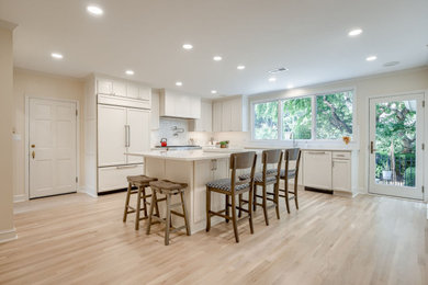 Large l-shaped light wood floor kitchen photo in Kansas City with an undermount sink, shaker cabinets, white cabinets, quartz countertops, white backsplash, subway tile backsplash, stainless steel appliances, an island and white countertops