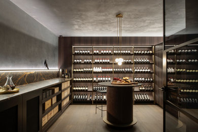 Cette photo montre une cave à vin tendance de taille moyenne avec un sol en bois brun, des casiers et un sol gris.