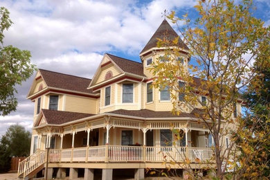 Photo of a large traditional three-storey yellow house exterior in Denver with wood siding, a hip roof and a shingle roof.