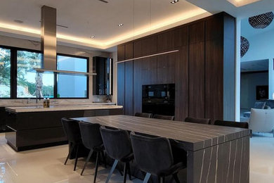 Example of a large minimalist u-shaped eat-in kitchen design in Miami with an undermount sink, flat-panel cabinets, dark wood cabinets, quartz countertops, black appliances, two islands and black countertops