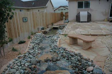 Photo of a large traditional drought-tolerant backyard stone landscaping in Denver.