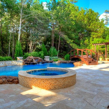 Natural Pool with rock waterfall, bridge, spa, and pergola