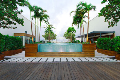Hot tub - large modern backyard rectangular infinity hot tub idea in Miami with decking