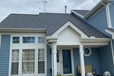 Inspiration for a blue two-story vinyl and board and batten exterior home remodel in Milwaukee with a shingle roof and a gray roof