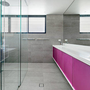 Immagine di un'ampia stanza da bagno padronale minimalista con ante lisce, ante viola, vasca da incasso, doccia a filo pavimento, piastrelle grigie, piastrelle in pietra, pareti bianche, pavimento con piastrelle in ceramica, lavabo da incasso, top in quarzo composito, pavimento grigio e porta doccia scorrevole