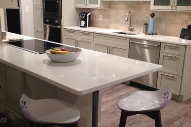 Inspiration for a transitional galley medium tone wood floor and brown floor eat-in kitchen remodel in Denver with an undermount sink, shaker cabinets, white cabinets, quartzite countertops, beige backsplash, stainless steel appliances and a peninsula