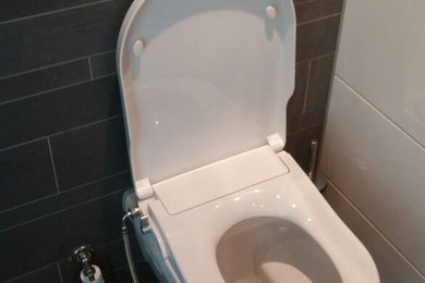 Design ideas for a mid-sized modern powder room in Amsterdam with a wall-mount toilet, brown tile, ceramic tile, ceramic floors and brown floor.