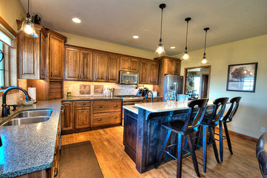 Example of a mid-sized classic l-shaped light wood floor open concept kitchen design in Other with a double-bowl sink, raised-panel cabinets, medium tone wood cabinets, beige backsplash, stone tile backsplash, stainless steel appliances, an island and laminate countertops
