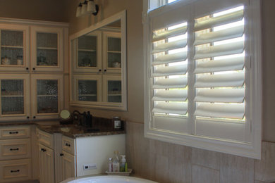 Drop-in bathtub - large traditional master beige tile and travertine tile beige floor drop-in bathtub idea in Omaha with beaded inset cabinets, white cabinets, brown walls, an undermount sink, granite countertops and brown countertops