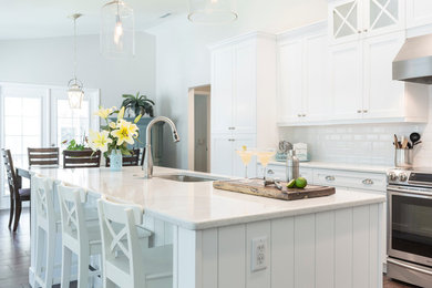 Large transitional l-shaped porcelain tile eat-in kitchen photo in Tampa with an undermount sink, shaker cabinets, white cabinets, quartz countertops, white backsplash, porcelain backsplash, stainless steel appliances and an island