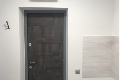 Пример оригинального дизайна: узкая прихожая среднего размера с белыми стенами, светлым паркетным полом, одностворчатой входной дверью, входной дверью из темного дерева и белым полом