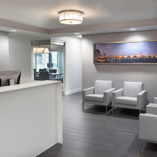 This is an example of a medium sized modern home office and library in Miami with grey walls, laminate floors, grey floors, a ribbon fireplace and a built-in desk.