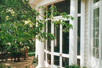Large elegant brick screened-in front porch photo in Other