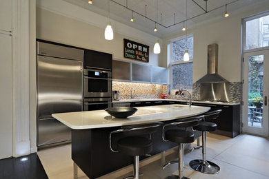 Large modern l-shaped kitchen in New York with flat-panel cabinets, black cabinets, stainless steel appliances and with island.