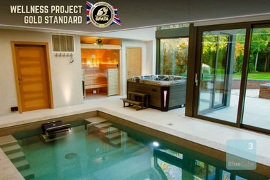 Small modern indoor rectangular pool in Other with a pool house and tile.