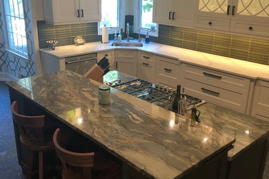 Example of a mid-sized transitional u-shaped gray floor kitchen design in New York with an undermount sink, shaker cabinets, white cabinets, quartzite countertops, green backsplash, matchstick tile backsplash, stainless steel appliances, an island and white countertops