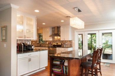 Inspiration for a mid-sized transitional l-shaped eat-in kitchen in Tampa with an undermount sink, raised-panel cabinets, white cabinets, quartz benchtops, metallic splashback, metal splashback, stainless steel appliances, painted wood floors and with island.