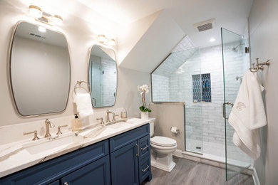 Photo of a mid-sized contemporary kids bathroom in Philadelphia with recessed-panel cabinets, blue cabinets, an alcove shower, a two-piece toilet, gray tile, ceramic tile, grey walls, vinyl floors, an undermount sink, engineered quartz benchtops, grey floor, a hinged shower door, white benchtops, a niche, a double vanity and a built-in vanity.