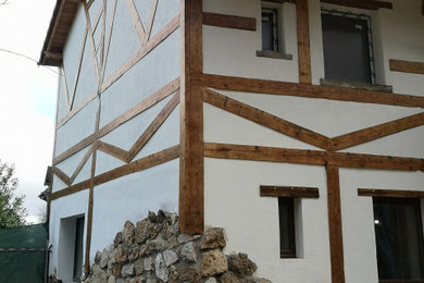 Diseño de fachada de casa blanca campestre de tamaño medio con revestimientos combinados, tejado a dos aguas y tejado de teja de barro