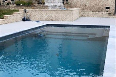 Foto de piscina de tamaño medio rectangular en patio trasero con losas de hormigón