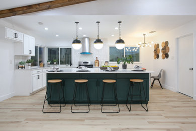 Example of a mid-sized single-wall laminate floor and beige floor eat-in kitchen design in Other with a drop-in sink, shaker cabinets, green cabinets, quartz countertops, multicolored backsplash, mosaic tile backsplash, stainless steel appliances, an island and white countertops