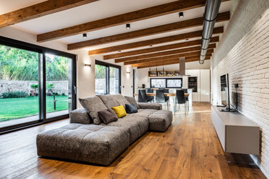 Photo of an industrial mezzanine living room in Rome with white walls, light hardwood flooring, brown floors, exposed beams and brick walls.